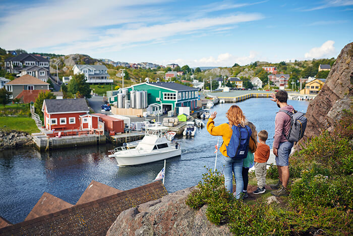 Photo of Quidi Vidi Village seen from the Sugar Loaf trail with family waving to a boat leaving dock