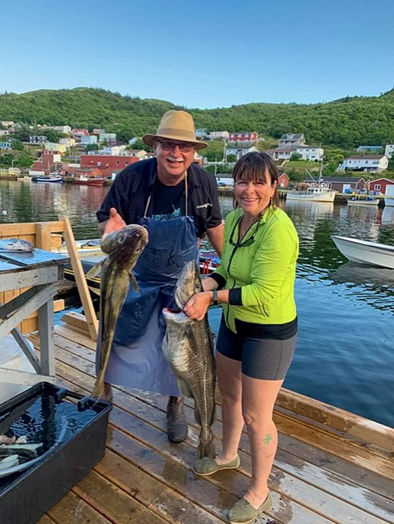 Man and woman on a dock hold a large cod just caught