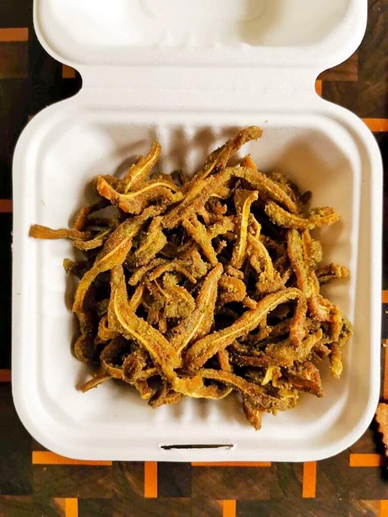 A white container stuffed full of Chinched snackable pigs ears