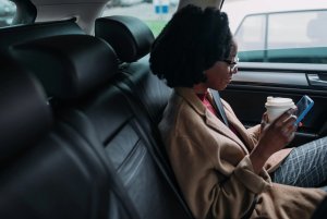 A woman sits inside a car using her cell phone.